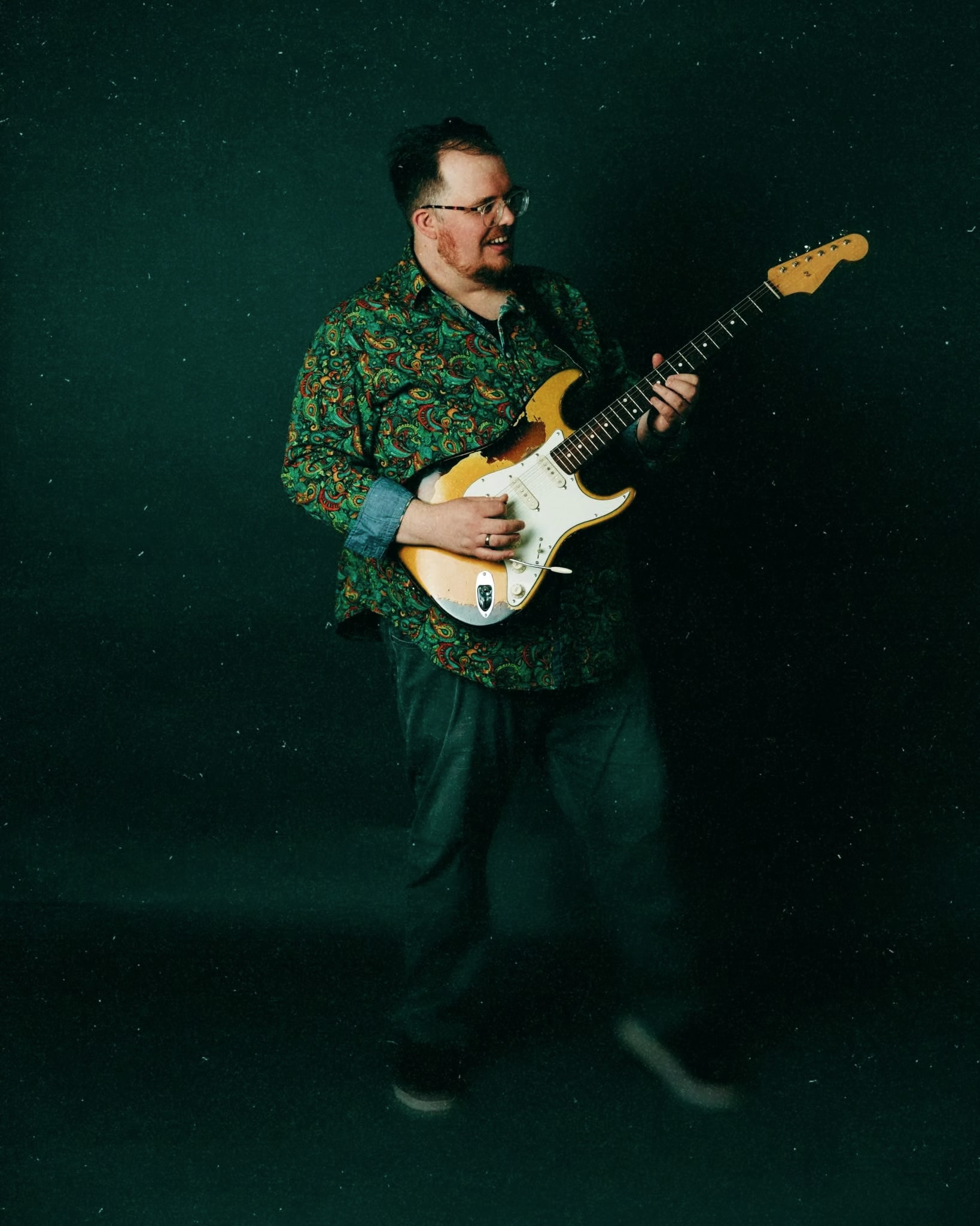 Brandon Scott Coleman playing a sunburst Stratocaster against a deep teal backdrop