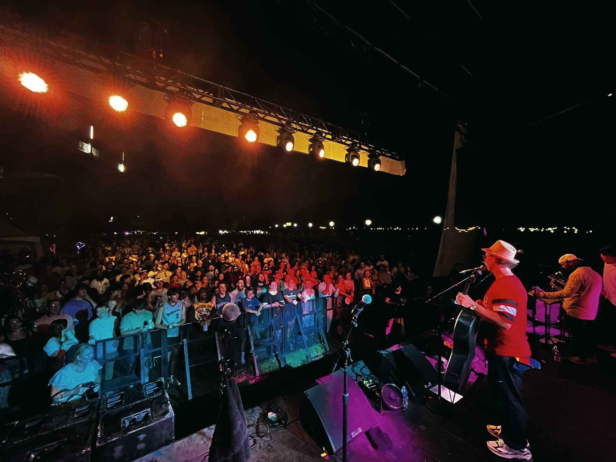 Ben Sollee playing cello to the crowd at Waterfront Wednesday in Louisville, seen from the stage under a lighting truss